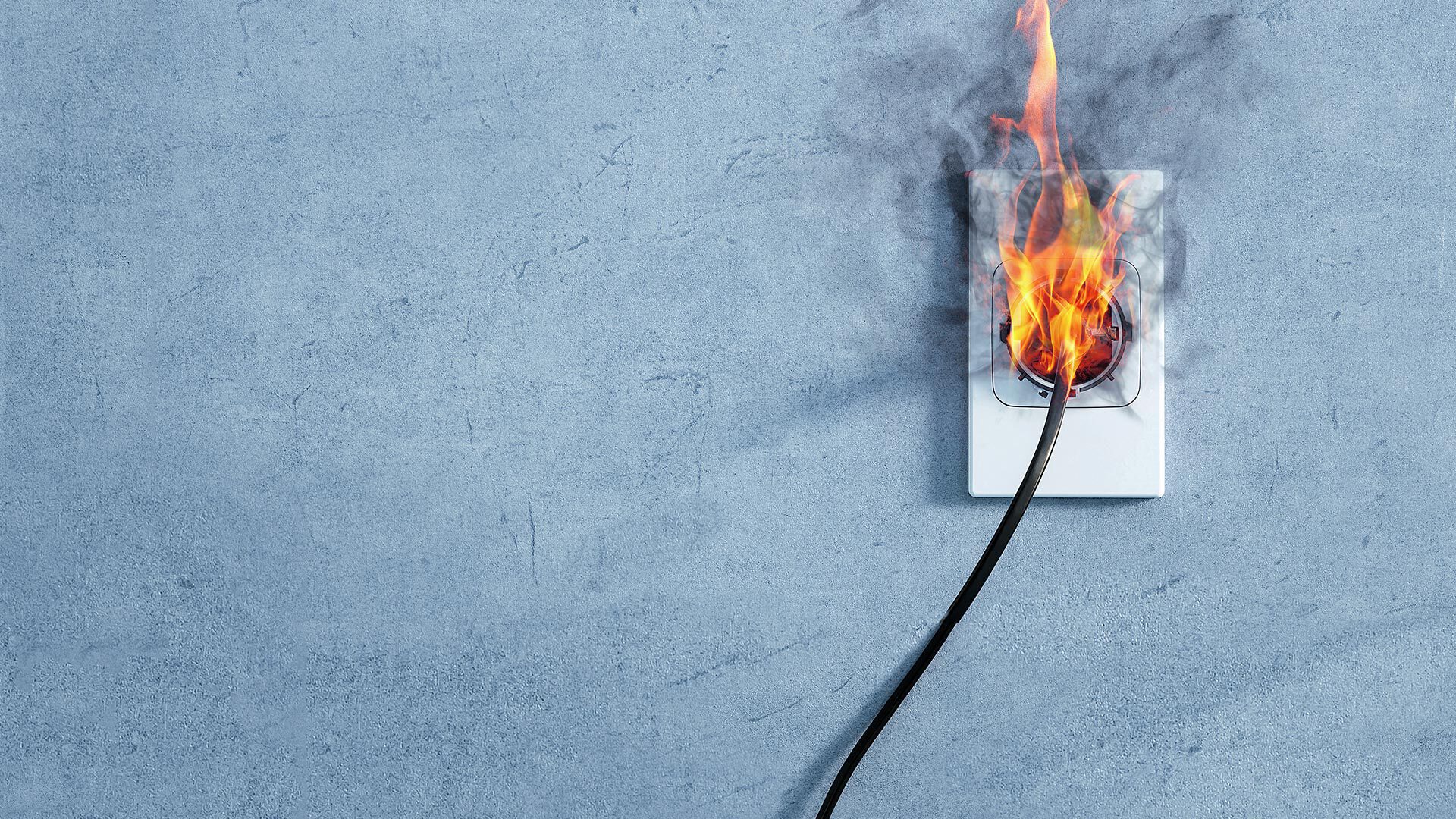 Power plug in a wall socket being dangerously on fire